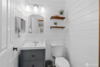 Stylish powder room offers shiplap accent walls, updated vanity, and a clean, modern look.