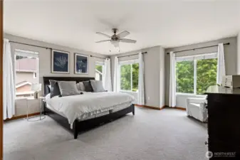 This expansive primary bedroom is bathed in natural light from several large windows.