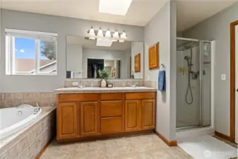 This en-suite primary bath features a dual vanity, a large mirror, and a glass-enclosed shower.