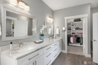 Double sinks, stone counter & walk - in closet beyond.