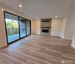 Open great room with sliding stacking doors to outdoor covered patio with gas fireplace