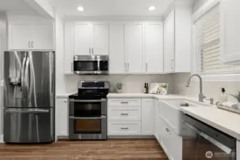 The bright kitchen with apron sink and stainless suite looks so sharp.