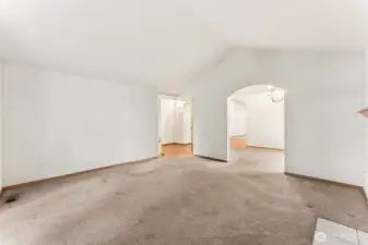 Looking across the living room toward the entry, the layout clicks into place. The arched doorway leads straight into the dining room and back around toward the kitchen, creating a circular floor plan that keeps you from hitting dead ends as you move through the house. The vaulted ceiling peak adds a nice architectural touch, and the recently installed gas furnace keeps the temperature steady with efficient forced air heat throughout the home.