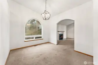 From the kitchen doorway you get a full view of this room and how flexible it really is. The large arched picture window brings in great light, the vaulted ceiling adds height, and the chandelier gives it a finished focal point. The arched opening back to the living room keeps everything connected. It works beautifully as a dining room, but it could just as easily become a library wall, a music space with a piano, or a quieter sitting room depending on what fits your life.