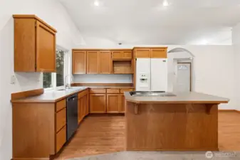 This angle shows why the floor plan feels comfortable to live in. The island seating invites company, the microwave shelf keeps appliances organized, and the arched opening ties the kitchen to the dining room without turning it into one big noisy room. Sightlines reach all the way to the front entry, making the house easy to navigate from the moment you walk in. The circular layout keeps spaces connected yet separate, so conversations, cooking, and relaxing can all happen at once without competing for attention.