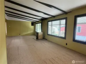 You can see it all here, the large open concept living room with vaulted ceilings with exposed rich dark beams. The pellet stove and wood wrapped windows.