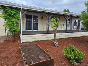Front entry of home with raised gardening beds, Strawberries planted. Newer non slip porch with pull down privacy screens