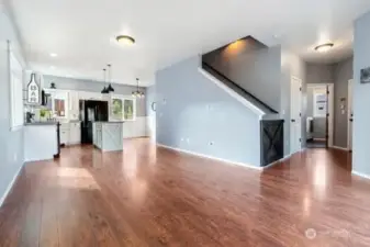 A great view of the open living room looking toward the kitchen and dining area and showcasing the staircase to the upper level with custom gate.