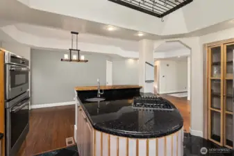 Kitchen includes double oven, island sink, gas range, and floor-to-ceiling glassware storage.