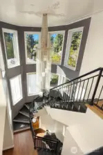 Incredible stairwell curving from the entry, to the the main and upper floors. Includes custom metal railings and wall tile, and 2-story wall of windows.