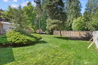 Fully fenced backyard is a great mix of open green grass and garden space.