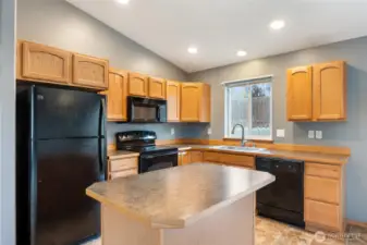 Bright kitchen with backyard view, generous cabinet space, and stylish black appliances included.