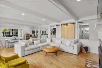 Open concept sunken living room with hardwood floors, ceiling beam detail and recessed lighting.