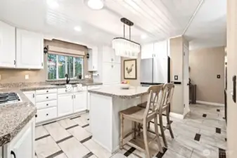 A white ship-lap type ceiling, beautiful island lighting, as well as can lighting, keep this kitchen light and bright.