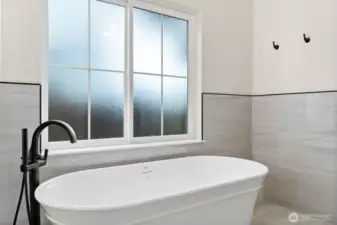 Spa-inspired primary bathroom with a freestanding Jacuzzi soaking tub and Moen floor-mounted tub filler with hand shower.