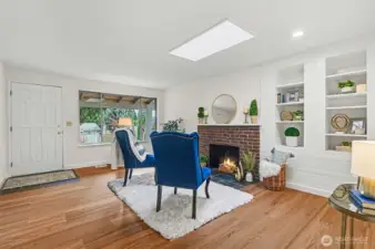 Cozy formal living room with fresh paint, new LVP floors, wood burning fireplace and built-in shelves.