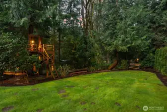 Custom tree house with swing set and exterior lighting.
