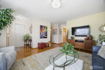 Looking across the living room toward the entry to the left with a large coat closet and the hallway to the 2nd bedroom and the kitchen to the right.