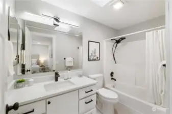 Primary Bath with skylight, New quartz counter top, lighting, mirror, fan, hardware, fixtures, toilet, tiled floor and resurfaced tub/shower too!