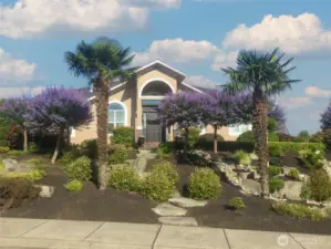 Stone step pathway winds through vibrant landscaping and sculpted greenery, creating a striking welcome to the front door.