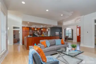 Bright and open great room seamlessly flows into the chef’s kitchen, featuring a spacious island, pendant lighting, and rich wood cabinetry—perfect for entertaining.