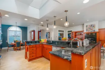 Stunning kitchen with cherry cabinetry, dramatic granite counters, and pendant lighting—open to the dining area with arched window, creating an ideal flow for entertaining.