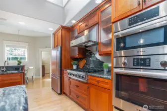 Chef’s kitchen featuring Bosch double ovens, a professional-grade Viking gas cooktop with striking granite backsplash, and cherry cabinetry that blends beauty with function.