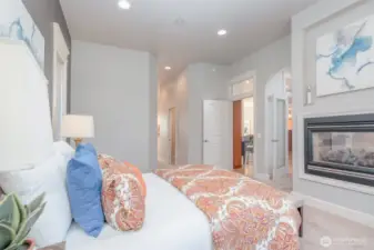 Expansive primary suite featuring elegant arches, transom windows, and an inset niche above the double-sided fireplace. Soft natural light and private entry to the spa-inspired ensuite bath create a true retreat.