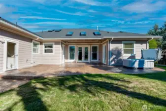 Backyard retreat with stamped concrete covered patio, relaxing hot tub, and manicured lawn—perfect for entertaining or quiet evenings outdoors.