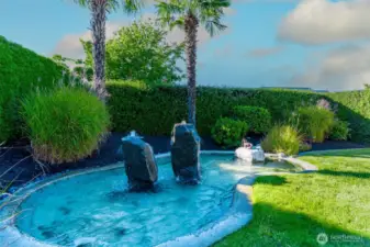 Tranquil backyard water feature with natural stone accents, tropical landscaping, and soothing sounds—adding to the serene retreat atmosphere.
