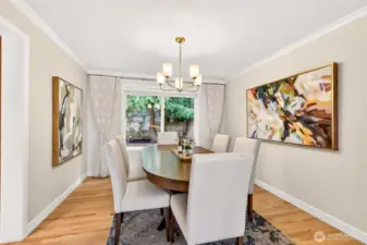 The dining room feels special and serene with crown molding, an updated chandelier, and a large picture window overlooking mature evergreens.