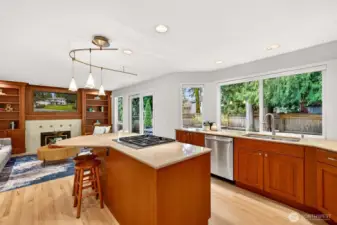 The heart of the home is a bright kitchen with expansive stone counters, a generous island with gas cooktop, and a wide window line that brings the backyard setting right into daily life.
