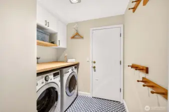 A renovated laundry room adds real function with built in storage, a durable work surface, and a complete washer and dryer set, plus thoughtful wall organization for daily essentials.