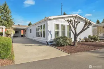 Street view of the home and the covered carport and parking area for 2 full sized vehicles. South facing windows and the West side windows all have blinds for privacy.