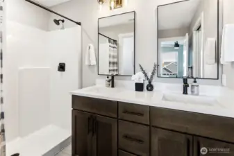 Dual sink vanity and walk in shower in primary bedroom