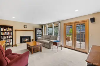 Large family room with gas fireplace, and French doors leading to deck.