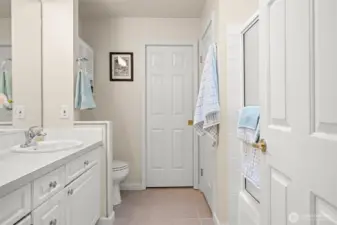 The primary bathroom. The door at the back opens to the walk-in closet. The door on the right, next to the hanging towel opens to a linen closet.