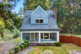 Overhead perspective showing the home’s charming roofline and surrounding evergreens, emphasizing its tucked-away setting among the trees.
