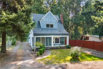 Aerial perspective highlighting the home’s front yard, detached garage, and additional driveway parking with RV space. The surrounding greenery adds to the property’s inviting appeal.