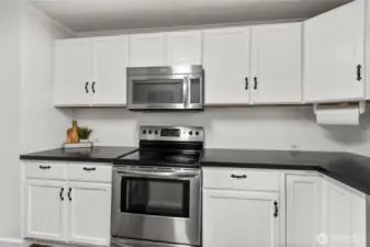 The kitchen features a modern appliance package, including a stainless steel oven and microwave, surrounded by fresh white cabinetry for a timeless, clean look.