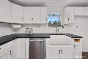 Close-up of the farmhouse sink and surrounding counter space, highlighting the kitchen’s balance of style and function with abundant storage and a bright window view.