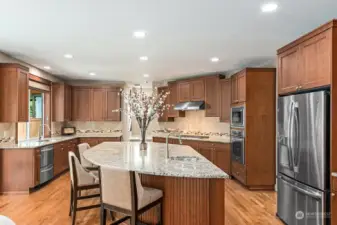 Spectacular island with sink, granite slab counter tops, custom tile backsplash, cherry cabinets and stainless appliances.