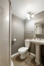 Bathroom with curved shower & pedestal sink.