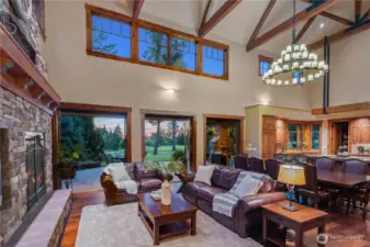 A spacious family room with a wall of French doors opening to outdoor living, a manicured yard, and scenic golf course views—seamlessly blending indoor comfort with outdoor elegance. You can see the flag of the 4th green in the distance.