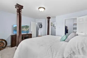 Looking through the primary bedroom with walk-in closet on the far right, then bathroom, hallway and living ahead.