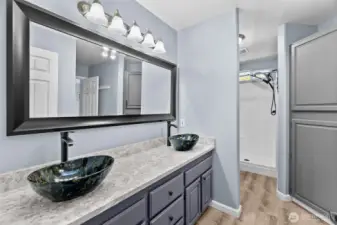 The primary bath with sparkling quartz counters, dual vanity vessel sinks, walk-in shower with new rainfal shower head, new toilet and fabulous storage!