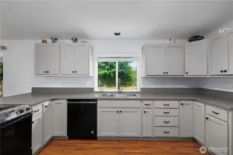 Bright and inviting kitchen with updated cabinets, black appliances, and a peaceful view out the window.