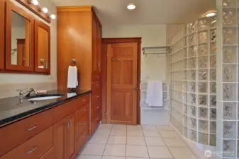 The primary bath features many built-in cabinets and drawers, plus a glass block shower.