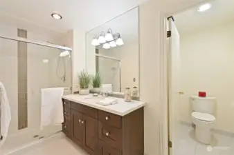 Primary suite bath is extra wide, generous vanity and convenient walk-in shower features glass enclosure.