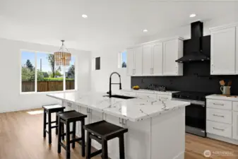 This stunning kitchen is the hub of the home. A massive island offers seating for informal dining. Sleek black accents play off of the detail in the quartz counters. Black tile back splash pull all of the details together.
